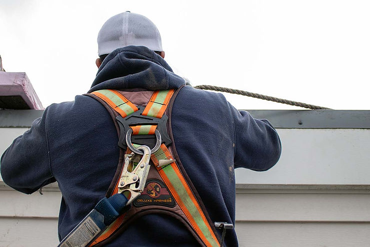 Dakota Roofing employee wearing a safety harness on a roof