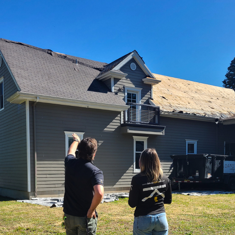 man and woman looking at a roof mid-tear off before the new shingles are installed