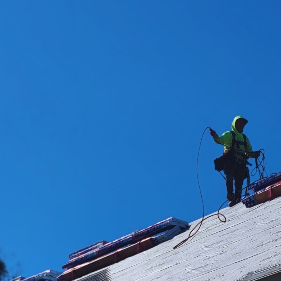 roofing installer on the peak of a roof preparing to place new shingles