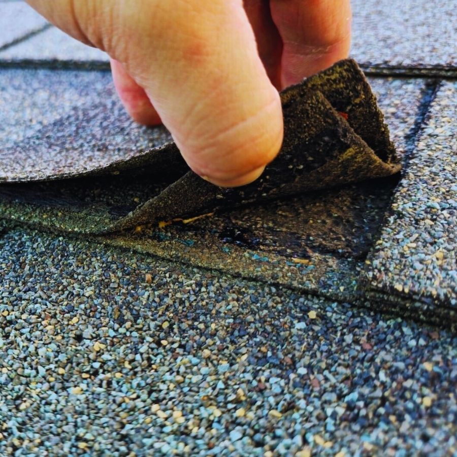 lifting shingles on and aging dark grey roof